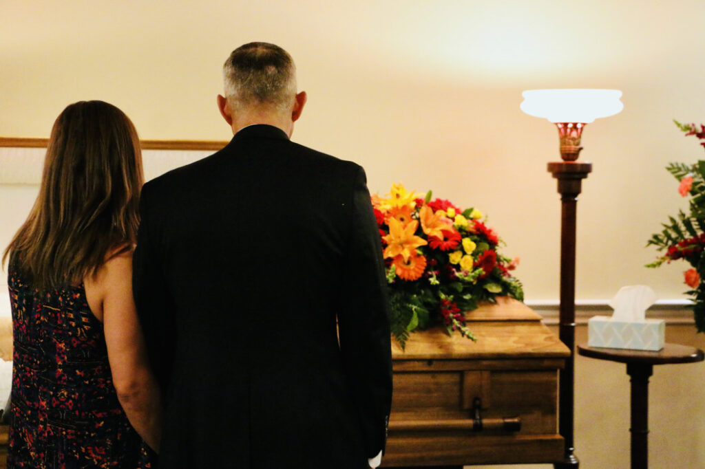 People standing in front of a coffin at a funeral