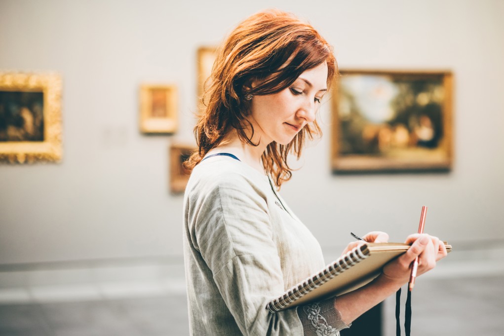 woman in an art museum holding a notebook and pencil - to illustrate that if you want dark academia inspired jobs museums are great places to start